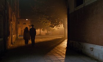 Movie still from “The Comfort of Strangers” (1990), directed by Paul Schrader – Two people walking down a street at night; Wide shot, Low angle