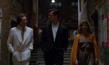 Movie still from “The Comfort of Strangers” (1990), directed by Paul Schrader – A man and two women standing next to each other in front of a building; Wide shot, Low angle