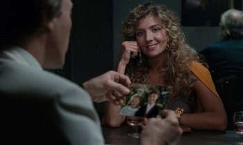 Movie still from “The Comfort of Strangers” (1990), directed by Paul Schrader – A woman sitting at a table with a man holding a picture; Close Up shot, Over the shoulder angle