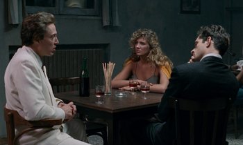 Movie still from “The Comfort of Strangers” (1990), directed by Paul Schrader – A group of people sitting at a table with wine glasses; Medium shot, Over the shoulder angle
