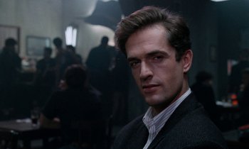 Movie still from “The Comfort of Strangers” (1990), directed by Paul Schrader – A person wearing a suit and tie; Close Up shot, Over the shoulder angle