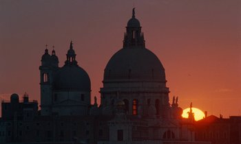 Movie still from “The Comfort of Strangers” (1990), directed by Paul Schrader – The sun is setting behind the domes of a building; Extreme Wide shot, Low angle