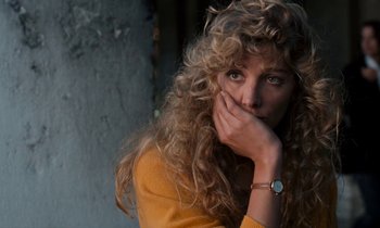 Movie still from “The Comfort of Strangers” (1990), directed by Paul Schrader – A woman with curly blonde hair wearing a yellow sweater; Close Up shot, High angle