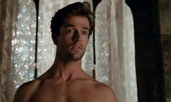 Movie still from “The Comfort of Strangers” (1990), directed by Paul Schrader – A man with no shirt is standing in front of a curtain; Close Up shot, Over the shoulder angle