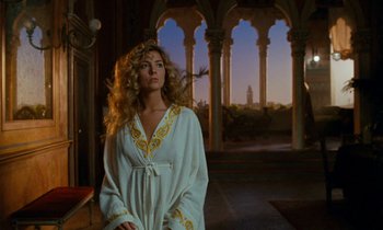 A woman in a white robe standing in a room with columns