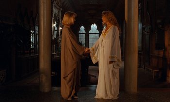 Movie still from “The Comfort of Strangers” (1990), directed by Paul Schrader – Two women dressed in ancient roman clothing shaking hands; Wide shot, Over the shoulder angle