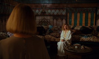 Movie still from “The Comfort of Strangers” (1990), directed by Paul Schrader – A woman sitting on a couch in a living room; Wide shot, Over the shoulder angle