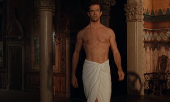 Movie still from “The Comfort of Strangers” (1990), directed by Paul Schrader – A shirtless man in a towel walking in a room; Medium shot, High angle