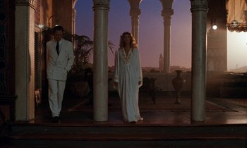Movie still from “The Comfort of Strangers” (1990), directed by Paul Schrader – A man and a woman standing in front of pillars; Wide shot, Low angle