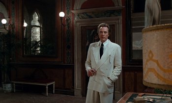 Movie still from “The Comfort of Strangers” (1990), directed by Paul Schrader – A man in a white suit standing in front of a door; Medium shot, Low angle