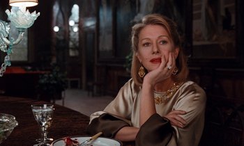 Movie still from “The Comfort of Strangers” (1990), directed by Paul Schrader – A woman sitting at a table with a plate in front of her; Close Up shot, Low angle