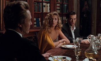 Movie still from “The Comfort of Strangers” (1990), directed by Paul Schrader – A group of people sitting at a table with plates of food on it; Medium shot, Over the shoulder angle