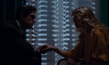 Movie still from “The Comfort of Strangers” (1990), directed by Paul Schrader – A man and a woman holding hands in front of a window; Medium shot, Over the shoulder angle