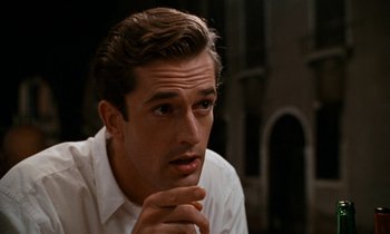 Movie still from “The Comfort of Strangers” (1990), directed by Paul Schrader – A man sitting down with his hand on his chin; Close Up shot, Over the shoulder angle