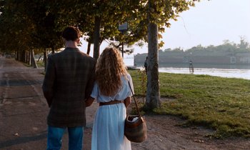 Movie still from “The Comfort of Strangers” (1990), directed by Paul Schrader – A man and a woman holding hands while standing next to each other; Wide shot, Over the shoulder angle
