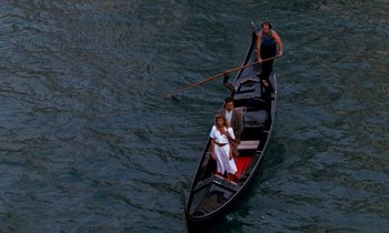 Movie still from “The Comfort of Strangers” (1990), directed by Paul Schrader – Two people are in a boat on a body of water; Wide shot, High angle