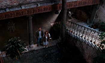 Movie still from “The Comfort of Strangers” (1990), directed by Paul Schrader – A man and a woman standing on the steps of a building; Wide shot, Overhead angle