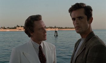 Movie still from “The Comfort of Strangers” (1990), directed by Paul Schrader – A couple of men standing next to a body of water; Medium shot, Low angle