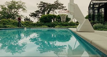 Movie still from “The Company Men” (2010), directed by John Wells – A view of a swimming pool with a basketball hoop in the background; Extreme Wide shot, High angle