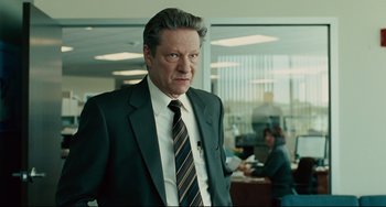 Movie still from “The Company Men” (2010), directed by John Wells – A person wearing a suit and tie; Medium shot, Over the shoulder angle