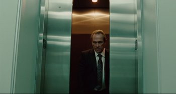 Movie still from “The Company Men” (2010), directed by John Wells – A man in a suit standing in an elevator; Medium shot, Low angle