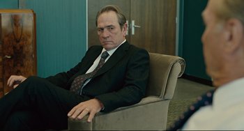 Movie still from “The Company Men” (2010), directed by John Wells – A man in a suit and tie sitting in a chair in an office; Medium shot, Over the shoulder angle