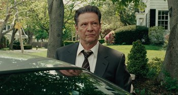 Movie still from “The Company Men” (2010), directed by John Wells – A man standing next to a car in a yard; Medium shot, Over the shoulder angle