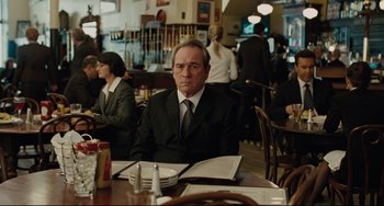 Movie still from “The Company Men” (2010), directed by John Wells – A man sitting at a table in a restaurant; Medium shot, Over the shoulder angle