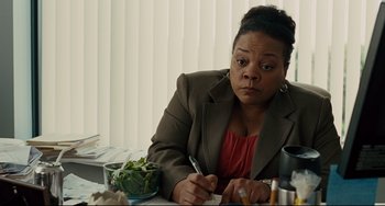 Movie still from “The Company Men” (2010), directed by John Wells – A woman sitting at a table writing on a piece of paper; Medium shot, High angle