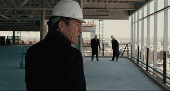 Movie still from “The Company Men” (2010), directed by John Wells – A man wearing a white hard hat in an unfinished building; Medium shot, Over the shoulder angle