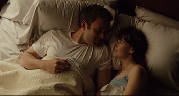 Movie still from “The Company Men” (2010), directed by John Wells – A man and a woman laying in a bed together; Medium shot, Overhead angle