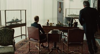 Movie still from “The Company Men” (2010), directed by John Wells – A man sitting at a table in front of a window; Wide shot, High angle