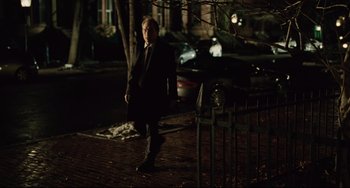 Movie still from “The Company Men” (2010), directed by John Wells – A man standing on a brick sidewalk at night; Wide shot, Over the shoulder angle