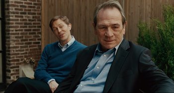 Movie still from “The Company Men” (2010), directed by John Wells – A man sitting next to another man in a suit; Medium shot, Over the shoulder angle