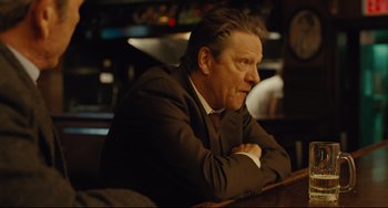 Movie still from “The Company Men” (2010), directed by John Wells – A man in a suit sitting in front of a bar; Close Up shot, Over the shoulder angle