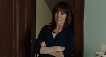 Movie still from “The Company Men” (2010), directed by John Wells – A woman standing with her arms crossed in front of a door; Medium shot, Over the shoulder angle