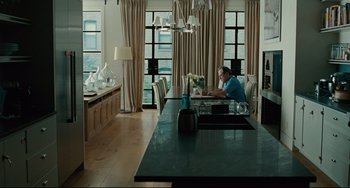 Movie still from “The Company Men” (2010), directed by John Wells – A man sitting at a table in front of a laptop computer; Wide shot, Over the shoulder angle