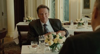 Movie still from “The Company Men” (2010), directed by John Wells – A man sitting at a table with a vase of roses; Medium shot, Over the shoulder angle