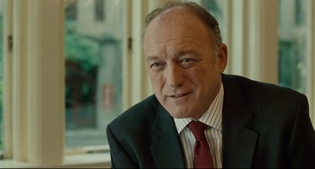 Movie still from “The Company Men” (2010), directed by John Wells – A man in a suit and tie sitting in front of a window; Close Up shot, Over the shoulder angle
