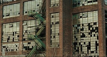 Movie still from “The Company Men” (2010), directed by John Wells – An abandoned building with a fire escape on the side; Extreme Wide shot, High angle