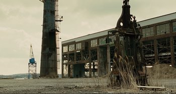 Movie still from “The Company Men” (2010), directed by John Wells – An old factory building with a tower in the background; Extreme Wide shot, Low angle