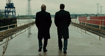 Movie still from “The Company Men” (2010), directed by John Wells – Two men are standing on a pier looking out at the water; Wide shot, Low angle