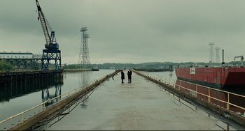 Movie still from “The Company Men” (2010), directed by John Wells – Two people walking across a bridge over a river; Extreme Wide shot, High angle
