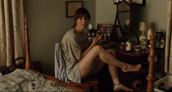 Movie still from “The Company Men” (2010), directed by John Wells – A woman sitting on top of a chair in a room; Medium shot, High angle
