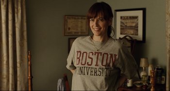 Movie still from “The Company Men” (2010), directed by John Wells – A woman standing in a room with a boston university t - shirt on; Close Up shot, Over the shoulder angle