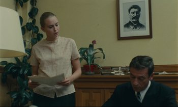 Movie still from “The Confession” (1970), directed by Costa-Gavras – A woman standing in front of a man in a suit; Medium shot, Low angle