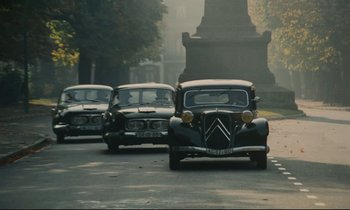 Movie still from “The Confession” (1970), directed by Costa-Gavras – A group of cars driving down a street; Wide shot, High angle