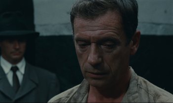 Movie still from “The Confession” (1970), directed by Costa-Gavras – A person wearing a shirt; Close Up shot, Over the shoulder angle