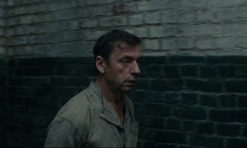 Movie still from “The Confession” (1970), directed by Costa-Gavras – A man standing in front of a brick wall; Close Up shot, High angle