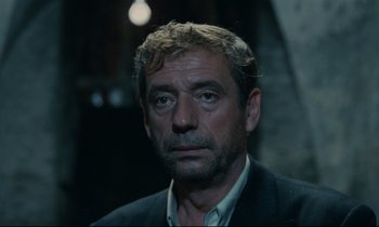 Movie still from “The Confession” (1970), directed by Costa-Gavras – A person wearing a suit and tie; Close Up shot, Low angle